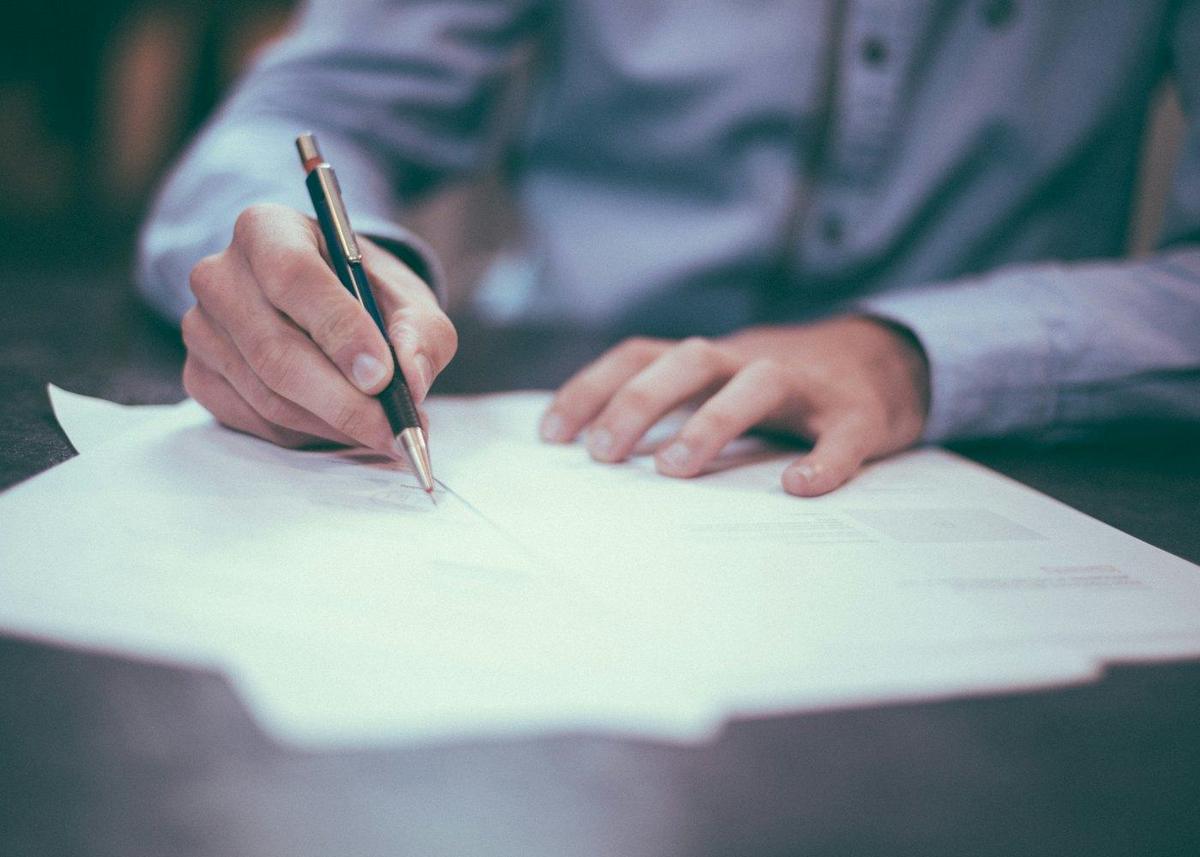 A person signing a mortgage renewal document with a pen