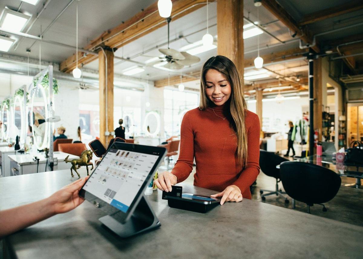 A small business owner taking a payment at the counter of her shop